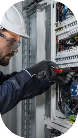 Électricien intervenant sur un tableau électrique dans un bâtiment professionnel.